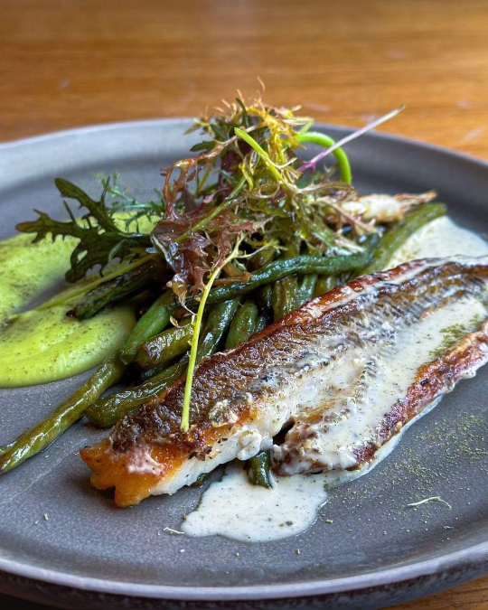 Un exemple d'un des plats servis au restaurant avec pêche du bateau, crème de fève, poêlé de haricots de verts et beurre blanc.